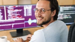 AI for HR Professionals: Man smiles at computer screen with code. AI in HR concept.