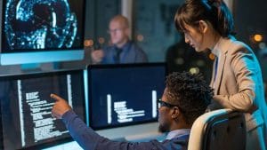 AI for DevOps: Developers collaborating on code. Team working with AI on multiple computer screens.