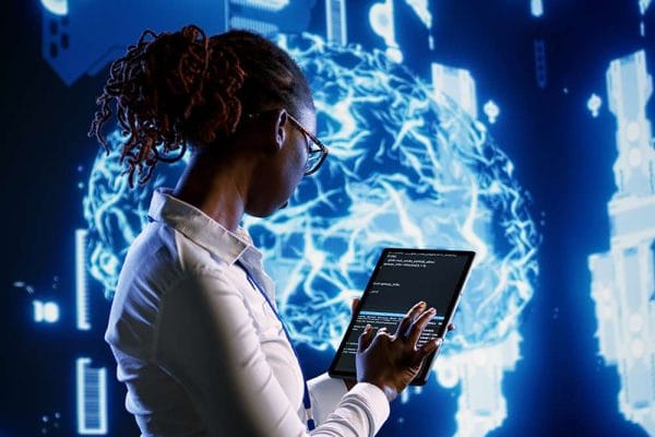 AI software engineer codes on a tablet. Digital brain background. Artificial intelligence concept.