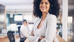 Smiling Customer Experience Manager with headset in office. Call center support representative.