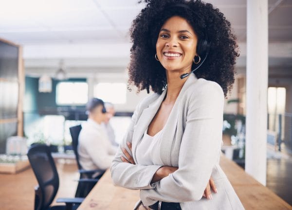 Smiling Customer Experience Manager with headset in office. Call center support representative.
