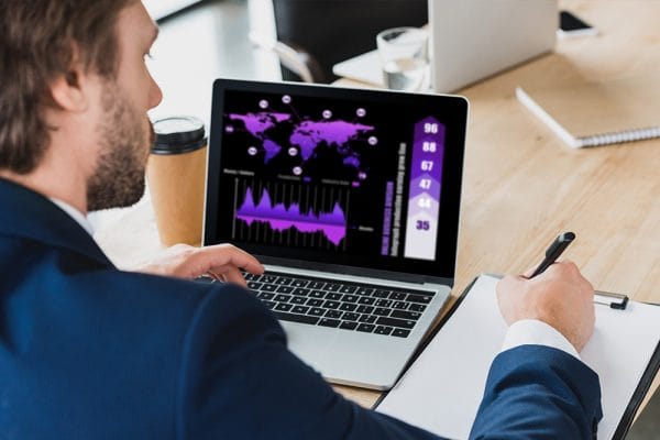 Data Structures and Algorithms in JavaScript: Man analyzing data on laptop with graphs and world map.