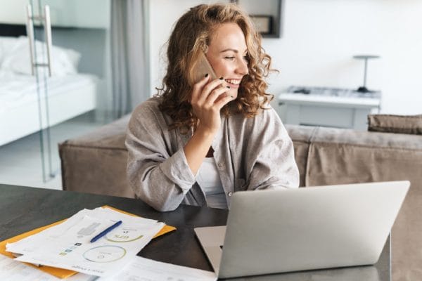 Executive Personal Assistant working at home. Woman on phone with laptop and paperwork.