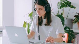 Office Admin: Woman with headphones using laptop and tablet. Online diploma in office administration.