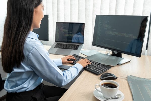 SecOps Engineer working at computer. Penetration Tester coding on multiple monitors. Cybersecurity professional.