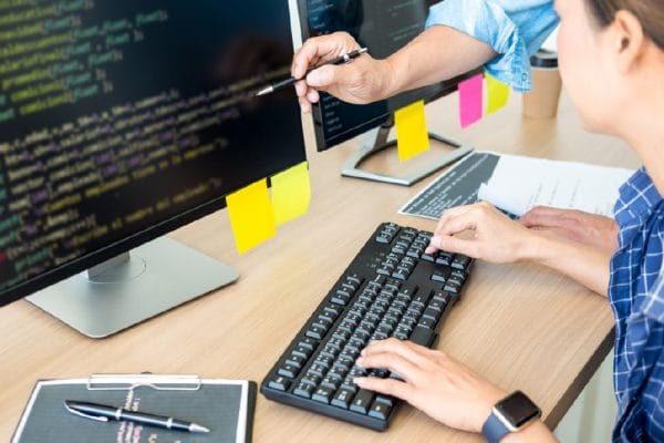 Security bundle: Programmer coding on desktop computer with security software.