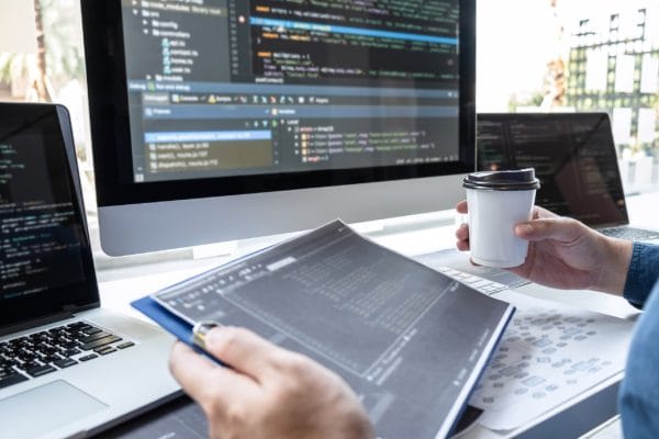 Software Project Analyst to Manager: Coder with laptop, coffee, and code on screen.