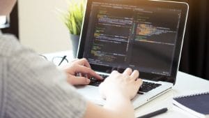Software project lead working as advanced Scrum Master on laptop with code.