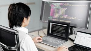 Developer working with code on multiple screens. Software engineering fundamentals.