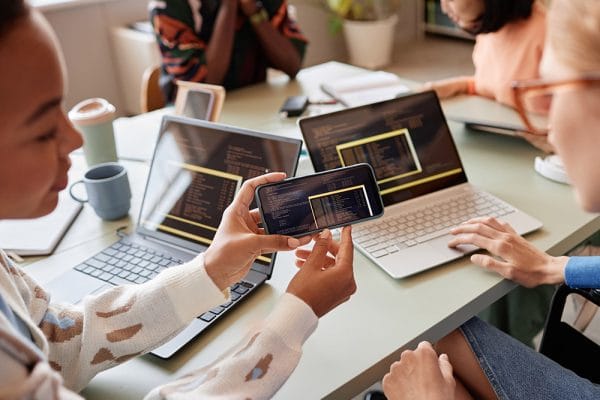 Interactive JavaScript site development: Developers working on code with laptops and mobile phone.