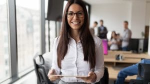 Smiling executive assistant holding tablet in office. Business woman career journey.