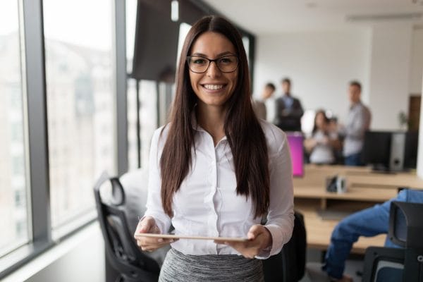 Smiling executive assistant holding tablet in office. Business woman career journey.