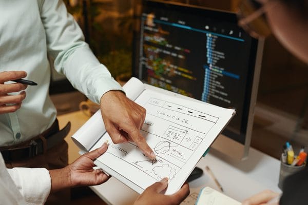 Interactive JavaScript Websites: Web developers designing a website layout. Computer screen with code in the background.