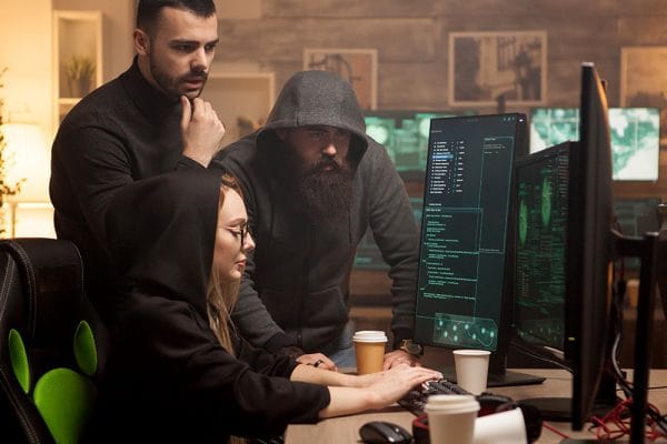 Introduction to Cybersecurity: Team analyzing code on computer screens. Cybersecurity experts working together.