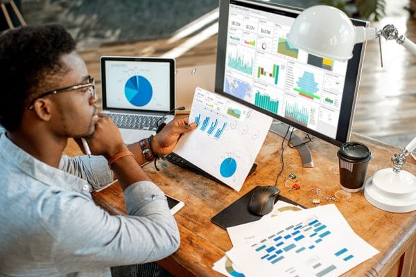Data analyst using Power BI. Charts and graphs on computer and paper.