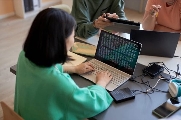Woman coding Python Flask web app on laptop. Programming, development, learning.
