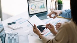 ICB Financial Accounting: Business professionals analyzing financial data on a tablet and laptop.