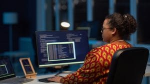 Woman using Linux on computer. Developer coding at desk with laptop. Using Linux.