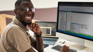 Man analyzing data with SQL. Developer smiling at computer screen with code. SQL programming.