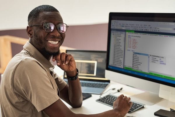 Man analyzing data with SQL. Developer smiling at computer screen with code. SQL programming.