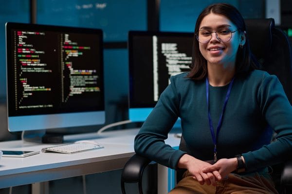 Creative coding with p5.js: Woman coding with two monitors displaying code. Programming with p5.js.