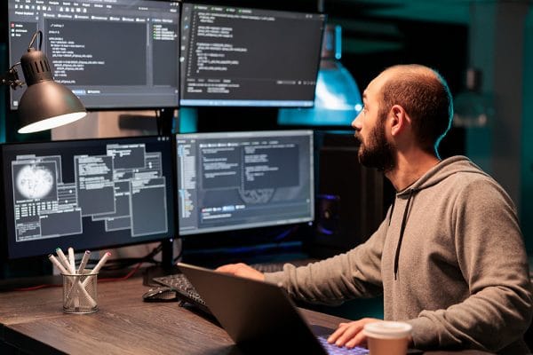 CISSP professional working on cybersecurity. Man coding on multiple monitors. IT security analyst at work.