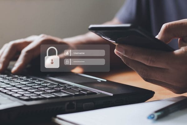 Ethical hacker using laptop and phone to access secure login. Cybersecurity concept.