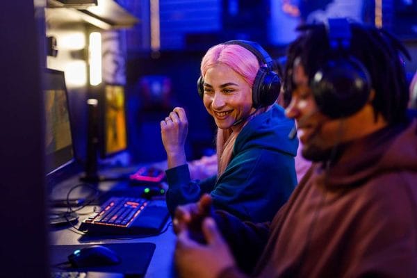 People developing a Phaser.js game. Coders with headsets, gaming keyboard, and computer screens.