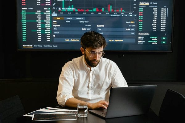 Google Data Engineer: Man analyzes financial data on laptop. Stock market charts displayed. Data analysis and engineering concept.