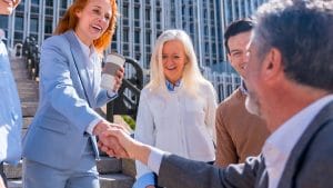 Public Relations Manager shaking hands with team. PR manager networking outdoors.