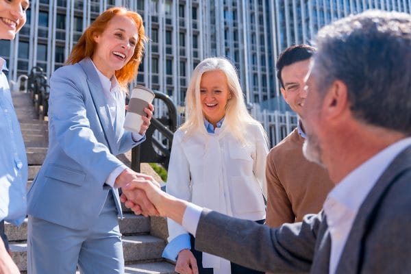 Public Relations Manager shaking hands with team. PR manager networking outdoors.