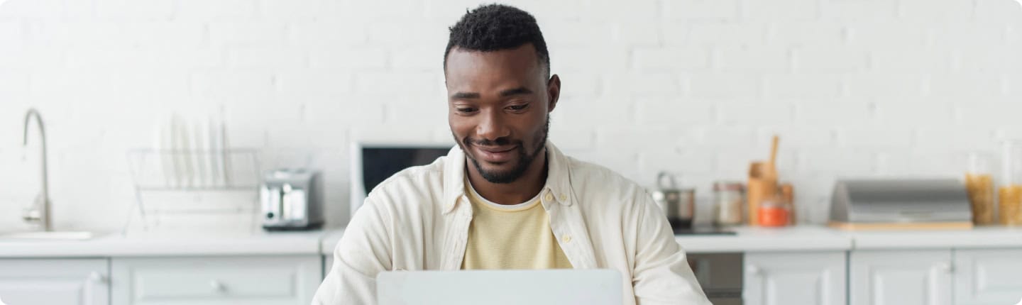 College SA: Man studies online using a laptop in a kitchen.